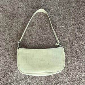 Beige axelväska med croco-mönster - Snygg beige axelväska med croco-mönster och stilren form. Väskan har ett smidigt axelband och stängs med dragkedja. Perfekt storlek för det viktigaste och ger en trendig touch till din outfit.