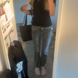 Grå bootcut jeans från Gina Tricot - Säljer ett par jätte snygga grå jeans från Gina Tricot i storlek 164. Modellen har låg midja, bootcut-ben och snygga slitningar för en cool vibe. Klassisk femficksdesign med dubbla knappar och dragkedja framtill. Perfekta för dig som gillar en avslappnad men trendig stil.