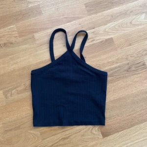 Svart ribbad linnetopp Gina Tricot - Säljer en svart ribbad linnetopp från Gina Tricot i storlek S. Toppen har smala axelband som korsas i ryggen och är croppad i modellen. Du står för frakten, vid mer info skriv