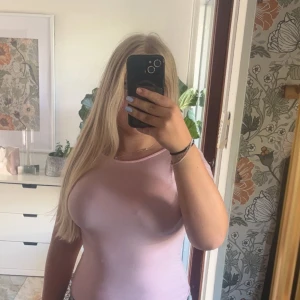 Ljusrosa croppad topp med öppen rygg - Säljer en ljusrosa croppad topp med korta ärmar och snygg öppen rygg. Toppen har en tight passform och är tillverkad i ett mjukt bomullsmaterial. Perfekt för dig som vill ha en enkel men ändå trendig look.