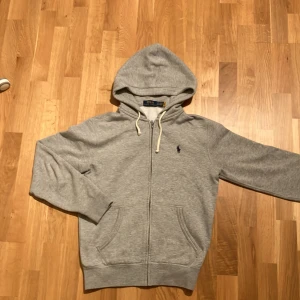 En ljusgrå zip-hoodie från Ralhp lauren - Raphe hoodie kostar 2295 Kr och är köpt på Zalando