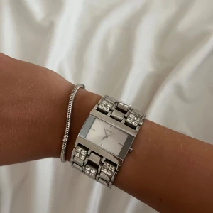 Silvrig Klocka från Guess - Jättefin klocka från Guess med bred länk i silverfärgad rostfritt stå. Köpt för några år sedan i guess butik för cirka 3000kr🥰