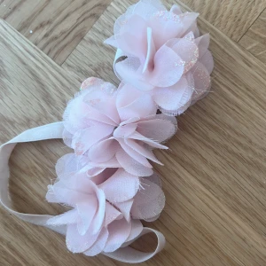 Rosa diadem med blommor och glitter - Superfint diadem med stora ljusrosa tygblommor och glittriga detaljer. Blommorna har en liten strass i mitten för extra bling. Perfekt accessoar när du vill sticka ut lite extra.