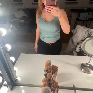 Grön ribbad linnetopp från New Yorker - Supersöt ljusgrön ribbad linnetopp från Amisu med spetsdetaljer längs v-ringningen. Toppen är ärmlös och har en croppad passform som sitter snyggt på kroppen. Perfekt för dig som gillar en enkel men ändå romantisk stil.