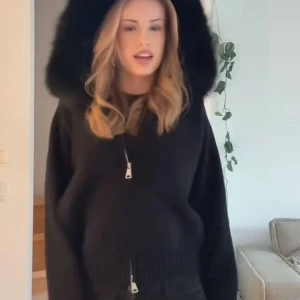 Svart stickad jacka  - Mysig svart stickad jacka med fluffig fuskpäls runt luvan. Jackan har dragkedja framtill och ribbade muddar vid ärmslut och nederkant. Perfekt för kalla dagar när du vill vara både varm och snygg. Nypris 899kr 