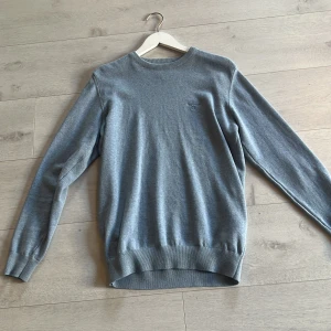 Ljusblå stickad tröja från Barbour - Säljer en stilren ljusblå stickad tröja från Barbour med diskret broderad logga på bröstet. Tröjan har rund halsringning och långa ärmar. Klassisk och enkel design som passar till mycket. Ny pris 1199. Vårat pris 550!. helt nytt skick!