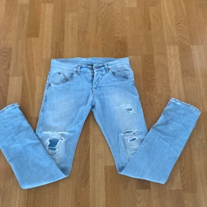 Ljusblå slitna jeansbyxor från Dondup - OBS; lämna pris förslag! Säljer ett par ljusblå jeansbyxor från Dondup med slitningar . Klassisk femficksmodell med dragkedja och knapp. Perfekta för en avslappnad och trendig look! 