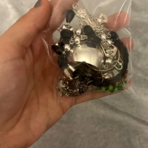 Mixade armband och smycken i svart, silver och färg - Flera armband och smycken i en mix av material och färger. Innehåller bland annat ett svart flätat armband, samt silvriga detaljer och berlocker. Perfekt för dig som gillar att variera din stil och vill ha någon liten påse men lite roliga smycken ❤️