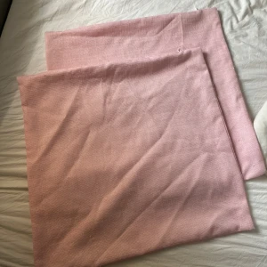 Ljusrosa kuddfodral  - Ljusrosa kuddfodral i 100% Polyester som aldrig kommer till användning längre. Finns några noppror och någon tråd som sticker ut (se bilder). FÖRST TILL KVARN!