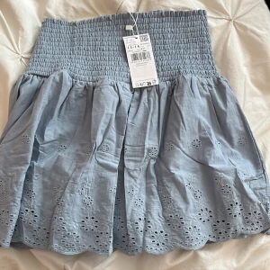 Blå  kortkjol från Mango - Superfin ljusblå kortkjol från Mango med  broderade blommor. Kjolen är gjord i bomull och är flowig. Kjolen har aldrig använts och har prislappen kvar. 🩵