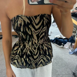 Glittrig axelbandslöd tubtopp i guld - Gold and black pattern strapless top, size uk 6, S, good condition, shipping from England - message me for details, shipping included in price 🩷