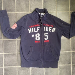 Vintage tröja från Tommy Hilfiger - Mörkblå ziptröja från Tommy Hilfiger med tryck på bröstet och ärmen. Snygg unik Vintage modell i storlek S. Perfekt tröja till sommarkvällar. Tveka inte skriva vid frågor!!!