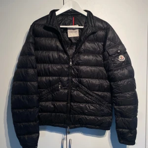 Moncler Agay Down Jacket  - Moncler Agay Down Jacket. Svart dunjacka med klassisk quiltad design. Jackan har två snedställda fickor med dragkedja och en extra ficka med logga på ärmen. Välanvänd men fortfarande kvar att ge. Storlek 3 vilket motsvarar Medium. Nypris 13 000kr. Pris kan diskuteras. Hör av dig för fler bilder eller info. 