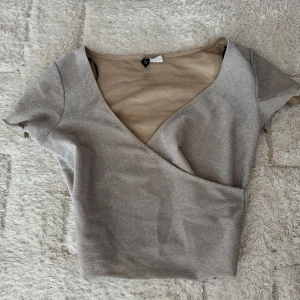 Glittrig fest topp - Säljer en snygg glittrig fest topp med korta ärmar och djup v-ringning. 