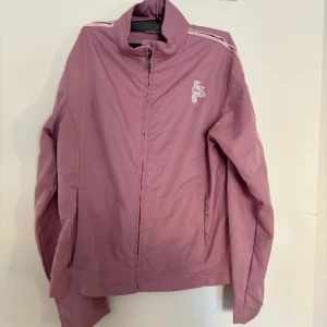 Sport jacka  - Sportjacka storlek M Jackan har två vita ränder längs axlarna och ärmarna, vilket ger den en sportig look. Färg gammalrosa  Fint skick