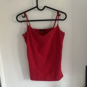 Röd linnetopp från Cubus - Säljer en enkel och snygg röd linnetopp från Cubus med smala axelband och v-ringad hals. Perfekt att matcha med jeans eller kjol för en stilren look. Toppens material känns mjukt och lätt.