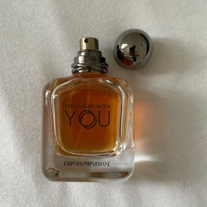 Emporio Armani Stronger With You - Emporio Armani Stronger With You är en parfym i en stilren glasflaska med rundad form och silvrig metallkork. Doften har en varm bärnstensfärgad vätska och flaskan har tydlig logga framtill. Perfekt för dig som gillar eleganta och moderna dofter. God skick 