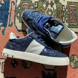 Valentino flycrews  - Snygga sneakers från Valentino Garavani med blå glitterdetaljer, skorna är i bra skick och har tagits hand om. Perfekta för dig som vill sticka ut med en glittrig och exklusiv look. Storlek 35, box medföljer. Pris kan diskuteras vid smidig affär. 