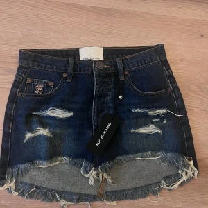 Mörkblå jeanskjol från One Teaspoon - Snygg mörkblå jeanskjol från One Teaspoon med slitna detaljer och fransig nederkant. Helt oanvänd! Med prislappen på. Nypris 1300kr
