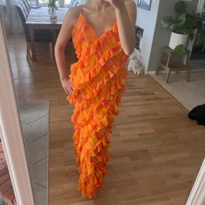 Färgglad långklänning med volanger - Fin långklänning orange med volanger från NAKD