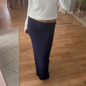 Mörkblå långkjol - Säljer en stilren mörkblå långkjol med tight passform. Kjolen har en enkel och klassisk design utan synliga detaljer och är perfekt för dig som gillar minimalistisk stil. Nelly , lite nertrampad och sliten längst ner, hål och trasigt , fråga om du vill ha bilder 