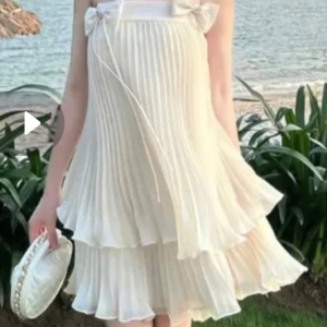 Set veckad topp + kjol med under shorts under kjol plisserad - Supersöt  linnetopp med tunna axelband och två små rosetter framtill. Toppen har plisserat tyg som ger ett luftigt och romantiskt intryck. Perfekt för varma dagar och enkel att matcha med olika underdelar.