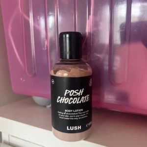 Lush Posh Chocolate Body Lotion - Lush Posh Chocolate Body Lotion i en 100g plastflaska med svart lock. Lotionen har en krämig, ljusbrun chokladfärg och doftar choklad. Perfekt för dig som älskar söta dofter och vill återfukta huden med en lyxig känsla. Ha i åtanke att denna är använd och har testats 2-3 gånger. Denna går ej att köpa separat på Lush 