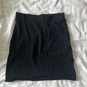 Svart kortkjol från H&M BASIC XS - Enkel svart kortkjol från H&M BASIC i stretchigt bomullsmaterial. Kjolen har en hög midja och rak passform, perfekt till crop tops eller oversized hoodies. Stilren och lätt att matcha med allt i garderoben.