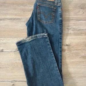 bootcut jeans Superlow - Säljer ett par klassiska blå levisjeans med bootcut-modell och låg midja. Jeansen har fem fickor, knapp- och dragkedjestängning samt kontrastsömmar. Märkta med 'Superlow Bootcut' i midjan. Perfekta för en avslappnad och tidlös look. 