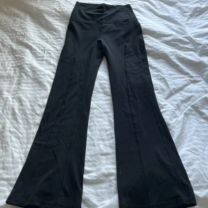 Svarta bootcut leggings med hög midja - Säljer ett par svarta leggings med bootcut och hög midja. Byxorna har en bred linning och är tillverkade i ett stretchigt material som passar perfekt till träning eller en avslappnad stil.
