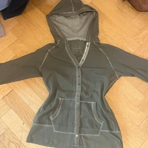  huvtröja med knappar 2000s stil - Unik huvtröja med knappar från märket Authentic George, köptes second hand och verkar vara från tidigt 2000-tal. Står ingen storlek men skulle gissa på XS-S, har trekvarts ärm