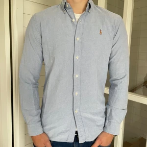 Ljusblå Ralph lauren oxford skjorta  - Säljer dennna snygga Ralph lauren skjorta den är i mycket bra skick! Den är i storlek M modell slim fit, 74 cm lång och 49 cm bred under armhålorna, hör gärna av dig vid frågor!