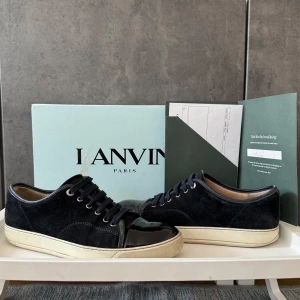 Navy Lanvin - Snygga navy blå sneakers från Lanvin i lyxig mocka med svart lackad tå och vita sulor. Superfina och stilrena – perfekta både till vardags och när du vill dressa upp looken lite.  ✔️ Storlek: 43 ✔️ Skick: 7.5/10 – lite slitage på botten av skon, annars väldigt fräscha ✔️kvitto och box medföljer 💬 Tveka inte att skriva om du har några frågor🙌