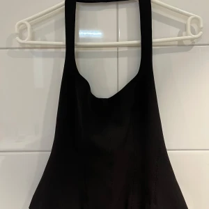 Svart croppad topp från Zara - Säljer en svart croppad topp från Zara med breda axelband och draperad halsringning. Toppen har en figurnära passform och är perfekt att styla till olika outfits. Nyskick. Aldrig använd! 