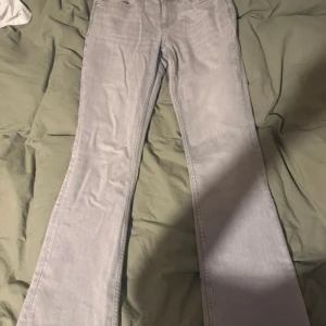 Ljusgrå bootcut jeans från Perfect Jeans - Säljer ett par ljusgrå bootcut jeans från Perfect Jeans i storlek 38. Jeansen har hög midja, klassiska fem fickor och är tillverkade i mjukt denimtyg. Snygg passform med utsvängda ben som ger en retrovibe. Aldrig använda 