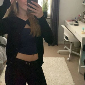 Svart kofta med knappar - Säljer en svart kofta med knappar framtill. Koftan har en klassisk passform och är långärmad, perfekt att slänga över en topp. Enkel och stilren design som funkar till många outfits.