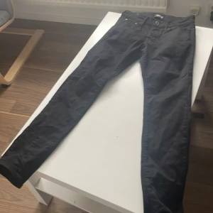 Svarta slim jeans Jack & Jones - Svarta jeans från Jack & Jones i modellen Slim/Glenn. Byxorna har en smal passform och klassisk femficksdesign. Tillverkade i stretchigt bomullsmaterial för extra komfort. Perfekta för dig som gillar en stilren och enkel look.