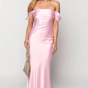 Ljusrosa axelbandslös långklänning - Superfin ljusrosa långklänning i glansigt satinliknande material. Klänningen är axelbandslös med offshoulder-detaljer och har en figurnära passform som faller snyggt längs kroppen. Perfekt för bal eller festligare tillfällen. Den kostar orginellt 745 kr + nedkommer en tullkostnad på 300 kr. Aldrig använd, endast provad!