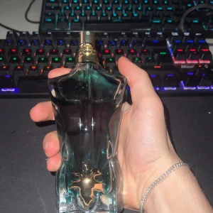 Jean Paul Gaultier Le Beau EDT - Ikonisk herrparfym i form av en manlig torso, flaska i glas med mörkgrön och svart toning samt gulddetaljer vid halsen. Doften är intensiv och elegant, perfekt för dig som gillar unika och lyxiga parfymer.