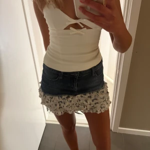 Jeanskjol med volangkant - Supersöt kort jeanskjol med volangkant i vitt tyg med små blommor. Säljs inte längre💕