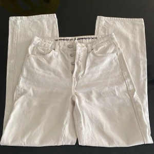 Vita/ljusbeiga jeans från Bik Bok - Ljusa jeans från Bik Bok med raka ben och hög midja. Byxorna har klassisk femficksdesign och knäppning med knappar framtill. Innerbenslängd: 81 cm. Midjemått: 36 cm rakt över.
