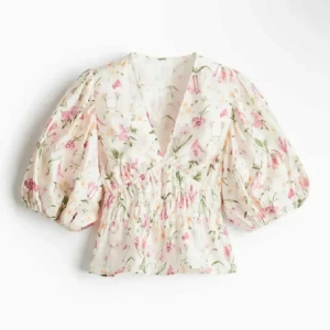 Blommig blus med puffärmar - Superfin blommig blus med v-ringning och puffiga trekvartsärmar. Blusen har smock i midjan och ett romantiskt blommönster i rosa och grönt på vit botten. Perfekt för vår och sommar! Helt slutsåld!!