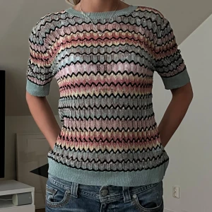 Pastellmönstrad stickad tröja från Dilvin - Säljer en stickad tröja från Dilvin med vågigt mönster i pastellfärger som rosa, mintgrön och gul. Tröjan har korta ärmar och ribbade muddar vid ärmslut och nederkant. Perfekt för dig som gillar färg och mönster!