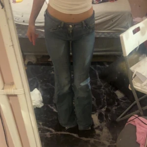 Blå bootcut jeans låg midja - Säljer ett par blå jeans med bootcut-modell och låg midja. Jeansen har klassisk femficksdesign och är tillverkade i denim. Perfekta för dig som gillar en avslappnad och trendig look.