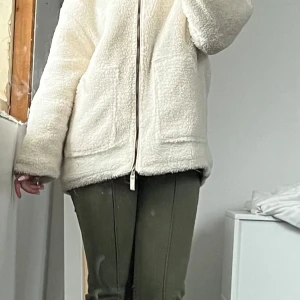 Vit teddyjacka med dragkedja - Mysig vit teddyjacka med rak passform och stora fickor framtill. Jackan har hel dragkedja och är tillverkad i fluffigt fleece-material som ger en chill vibe. Perfekt för lager-på-lager och funkar fett bra till både jeans och mjukis. Perfekt nu till hösten. Tveka inte att skriva vid frågor💕