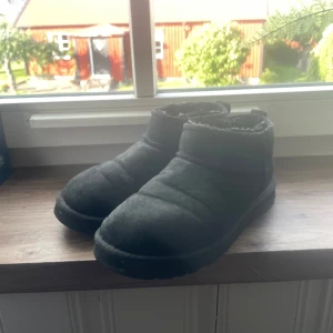 Svarta mini uggs - Mysiga svarta UGG boots i mocka med rund tå och fluffigt foder på insidan. Perfekta för kalla dagar, väll använda men inga hål eller liknande utan bara lite smuts . priset går att diskutera 
