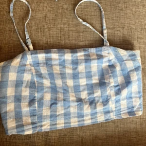 Blåvit rutig croppad linnetopp - Supersöt croppad topp med tunna axelband i blåvitt rutigt mönster. Så så fin verkligen, står storlek M på lappen men då den är croppad sitter den lite mer som Xs/s