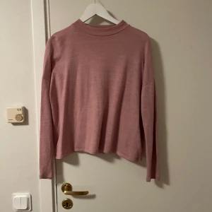 Ljusrosa långärmad tröja från Cubus - En stilren ljusrosa långärmad tröja från Cubus med rak passform och högre rund halsringning. Perfekt att matcha med jeans eller kjol för en chill look. Mjuk och skön, passar dig som gillar enkel och clean stil.Katt finns i hemmet 