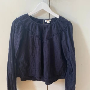 Mörkblå blus med volang från Gina Tricot - Supersöt mörkblå blus från Gina Tricot med diskret prickigt mönster och volangdetalj över bröstet. perfekt för dig som gillar en chill men ändå sötstil.