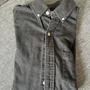 Svart overshirt  - Stilren svart overshirt i tidlös design – perfekt som lätt jacka eller lager-på-lager-plagg. Tillverkad i ett robust men bekvämt material som håller formen och ger en avslappnad, modern look. Passar både till vardag och utekvällar. Matcha med jeans, chinos eller över en hoodie för en trendig stil året runt.